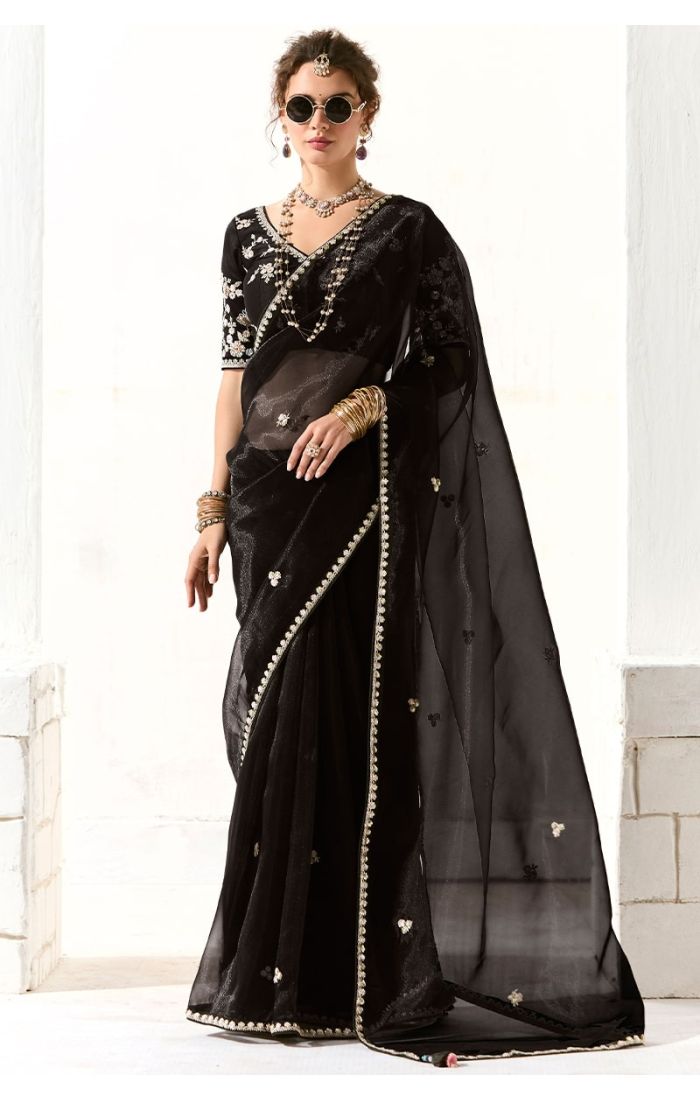 Model wearing black organza saree with heavy embroidery and lace border