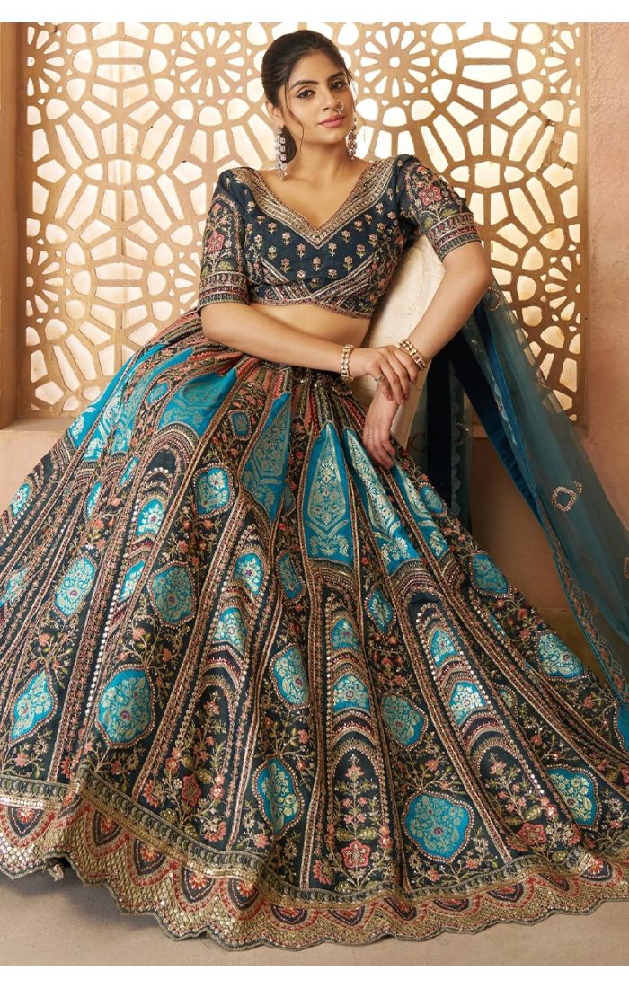Seated bridal look showcasing full flare of blue Banarasi lehenga with intricate embroidery
