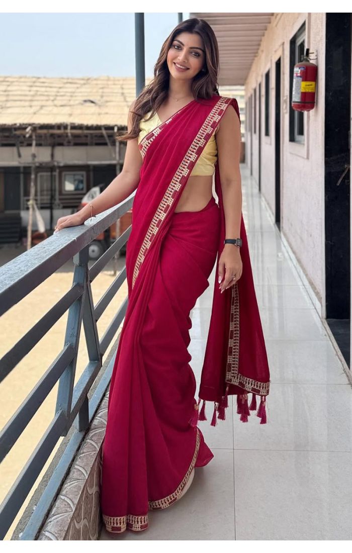 Woman wearing a maroon cotton blend saree with thread work and tassel border, paired with a sleeveless yellow blouse – perfect for casual and festive occasions.