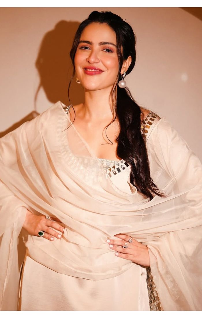 Close-up of woman in an ivory sharara set highlighting the mirror embroidery on the neckline and soft dupatta.