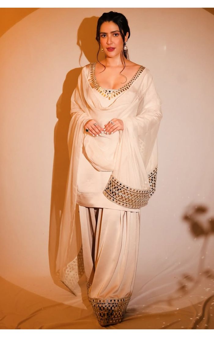 Close-up of woman in an ivory sharara set highlighting the mirror embroidery on the neckline and soft dupatta.