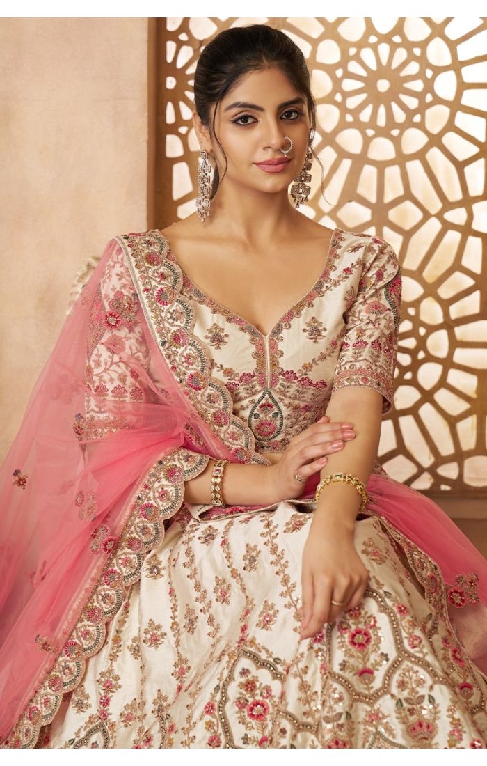 Bride in panelled cream lehenga with paisley embroidery and pink net dupatta