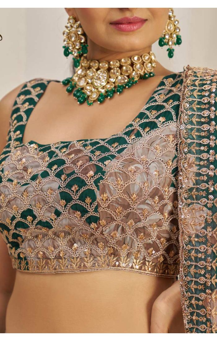Model posing in emerald green floral net lehenga choli with matching dupatta.