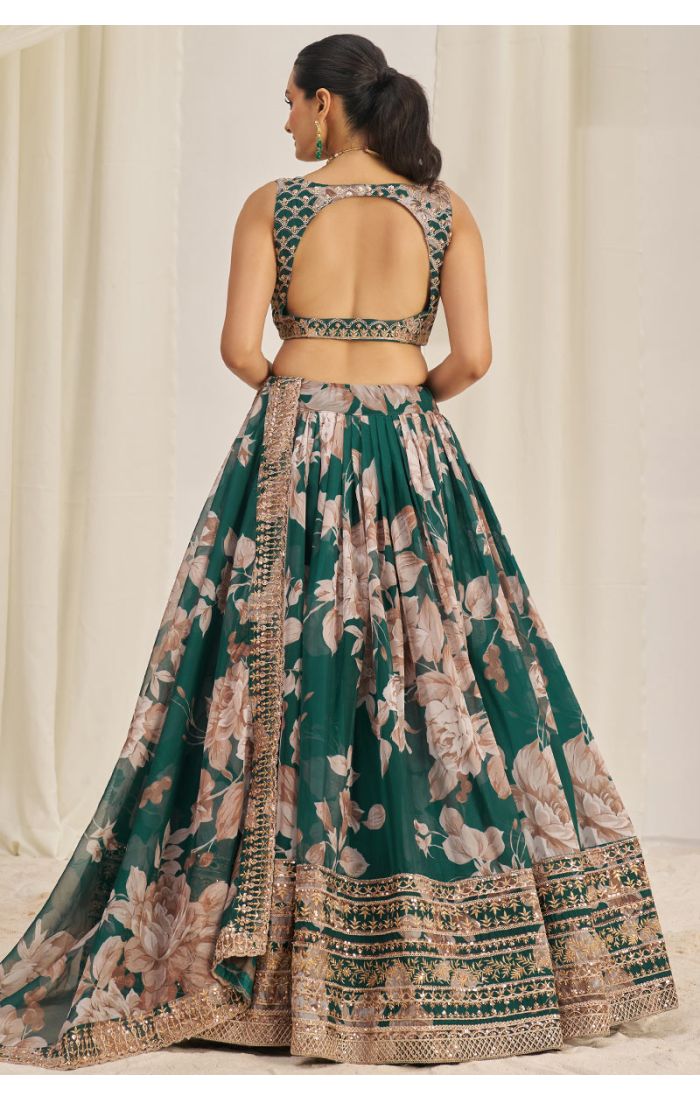 Model showing back design of emerald green floral lehenga choli with designer cut-out.
