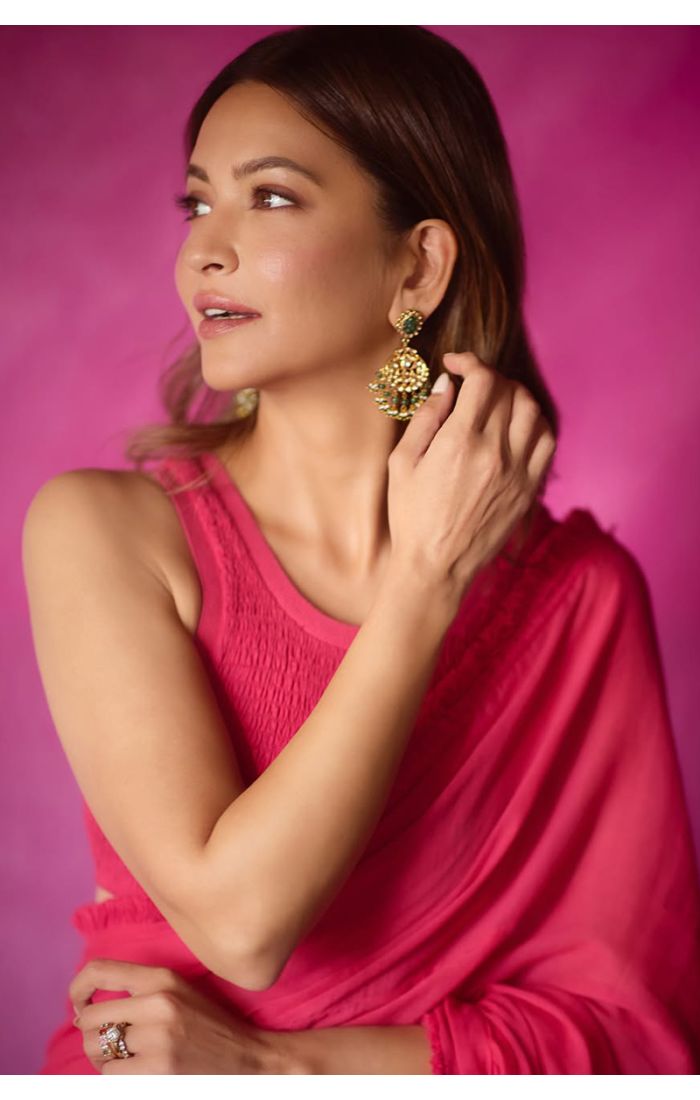 Woman in fuchsia sleeveless blouse styling a georgette saree