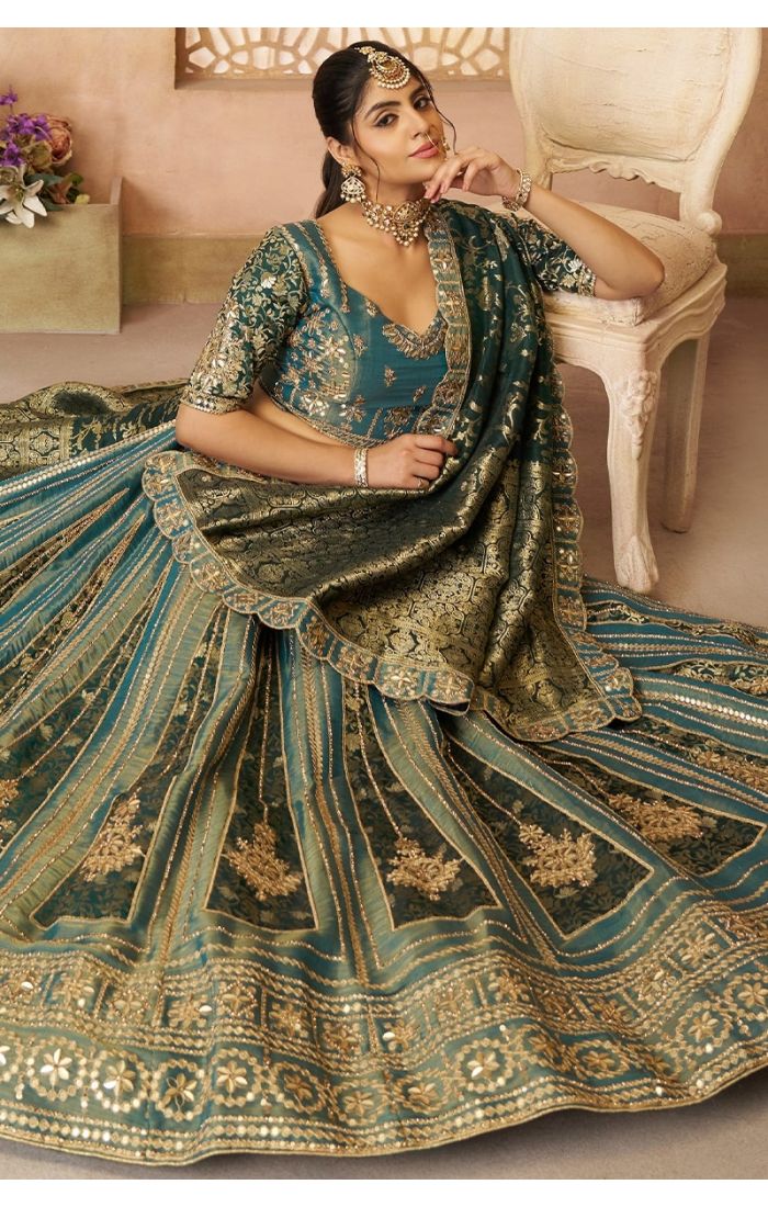 Elegant seated pose showing the flow and grandeur of green bridal lehenga with Banarasi dupatta.