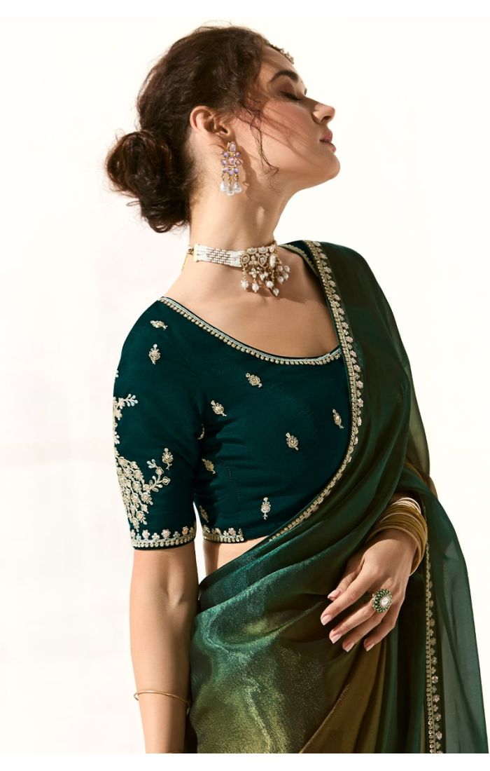 Side view of model wearing green tissue silk saree with gold bangles and choker necklace – traditional festive look.