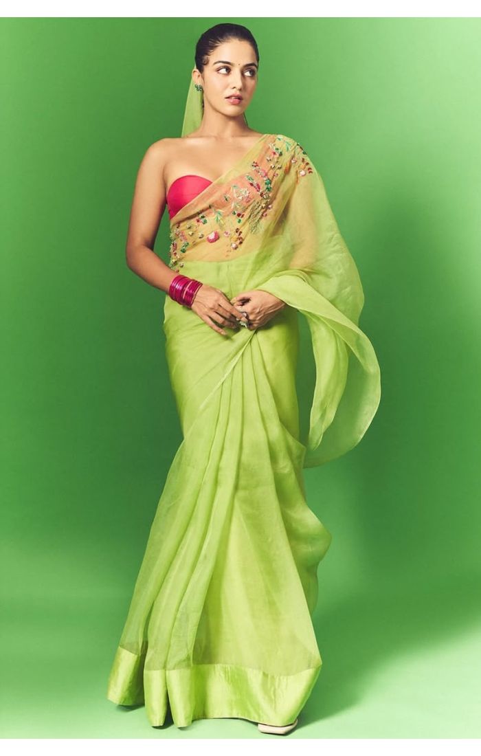 Full-length view of light green organza saree draped on model with flowing pallu and festive styling.