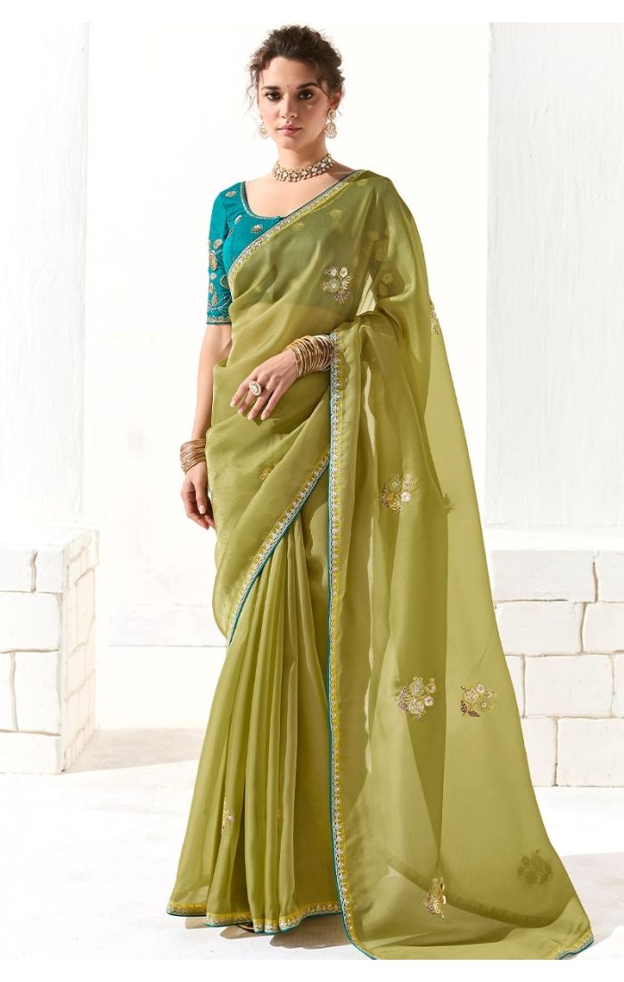 Model wearing light parrot green organza silk saree with blue embroidered blouse – front view
