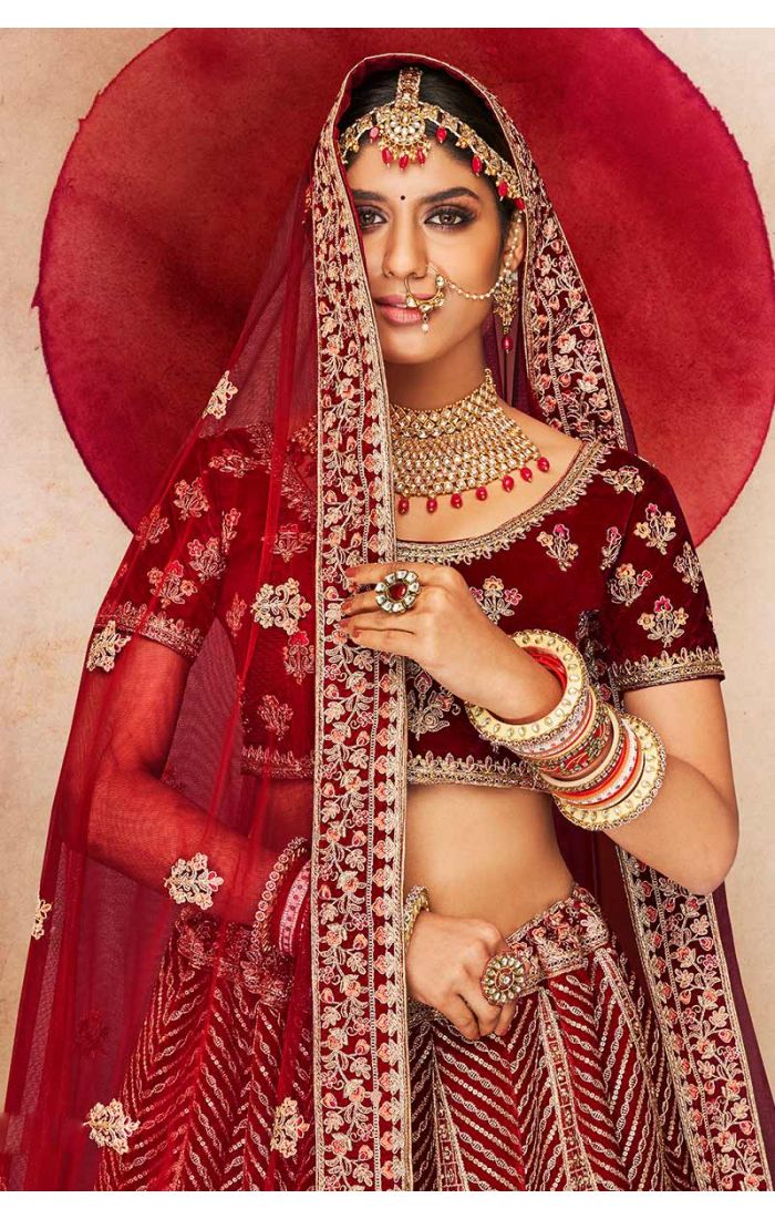 Close-up of maroon velvet bridal lehenga blouse with heavy peacock and floral embroidery, luxury bridal couture by Appelle Fashion.