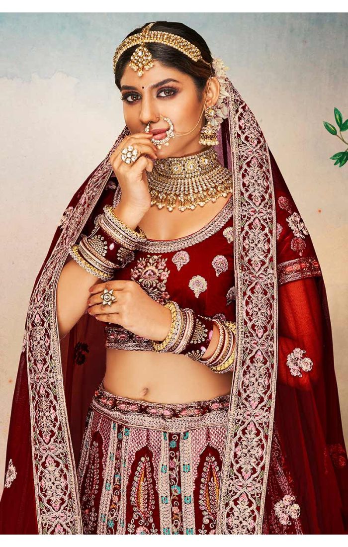 Close-up of maroon velvet U neck blouse with heavy floral embroidery and ornate dupatta, luxury bridal ensemble.