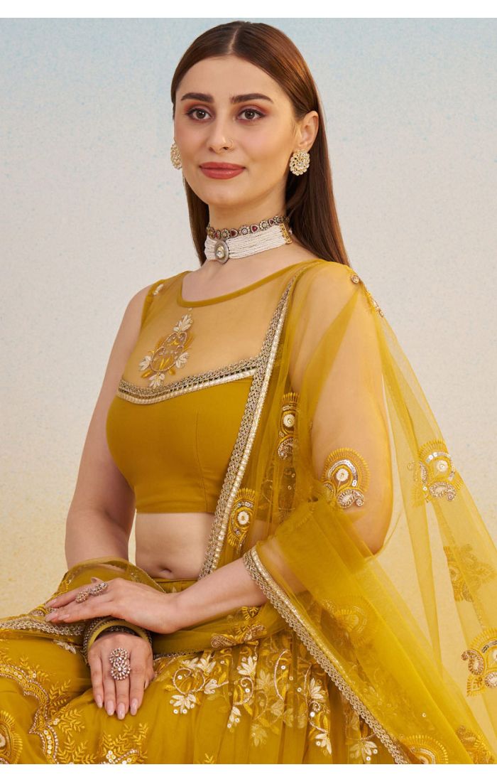 Detailed shot of mustard yellow lehenga blouse and embroidered dupatta with sequins and zari, designer ethnic fashion.