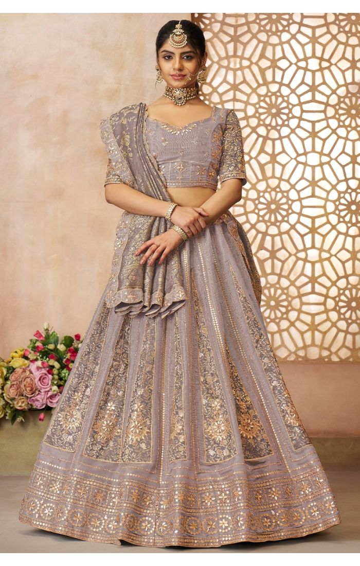 Onion-colored bridal lehenga with golden zari panels and brocade silk embroidery for weddings.