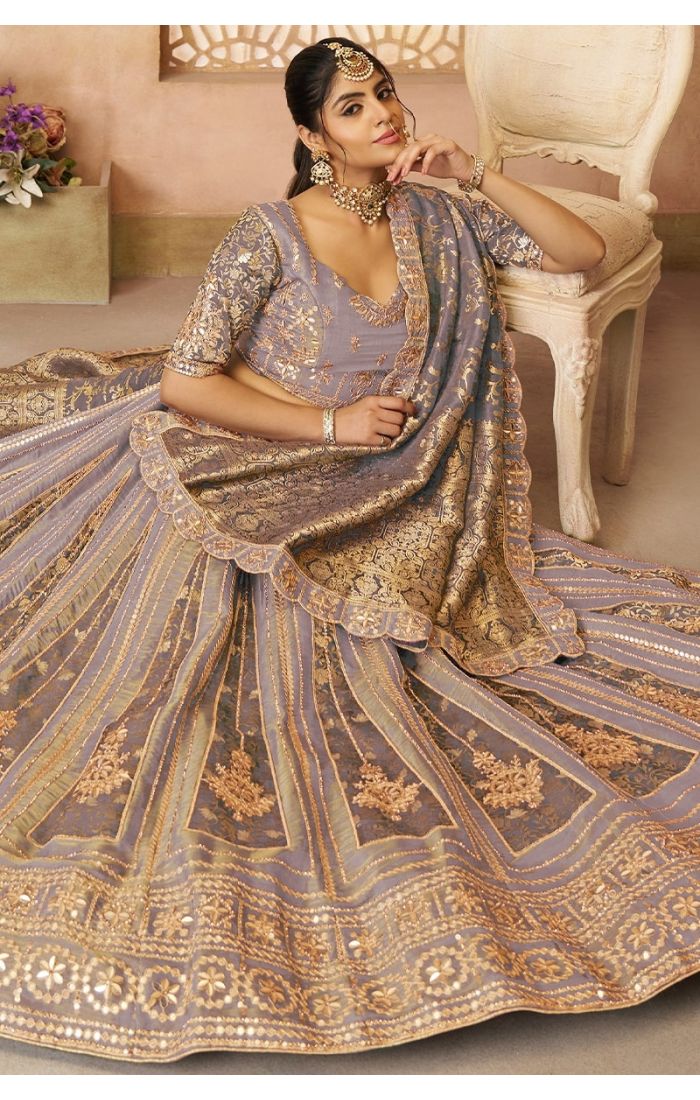 Regal onion pink Banarasi bridal lehenga in seated pose showing fabric texture and zari work.