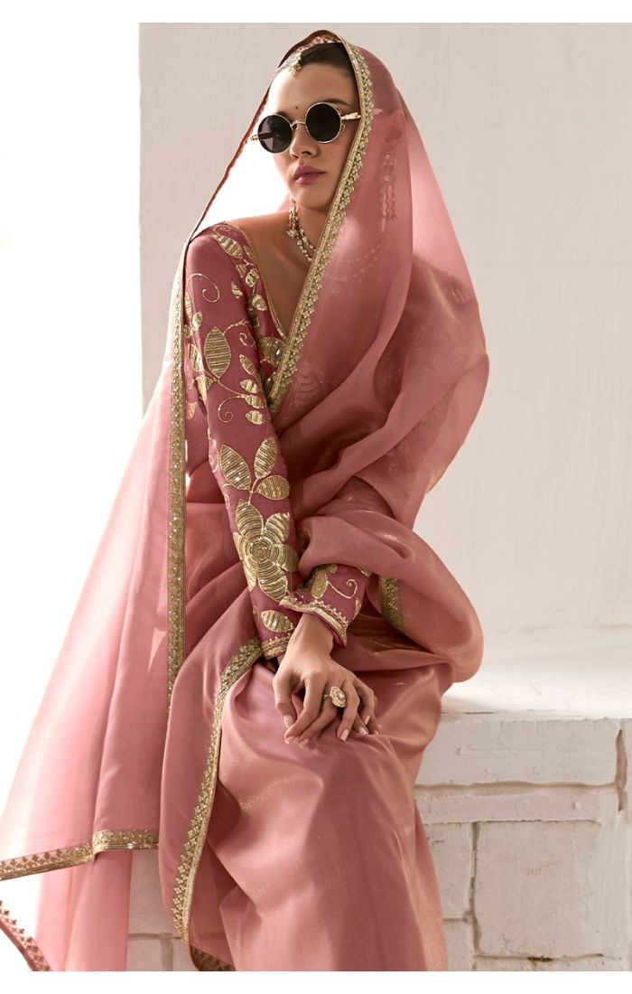  Seated model in peach saree showing embroidered blouse and gold lace border