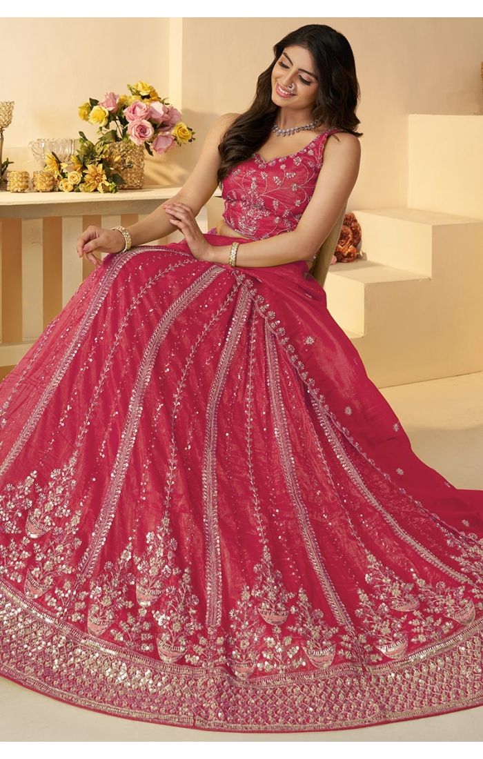 Bride in pink lehenga sitting, showcasing detailed hand embroidery and flare
