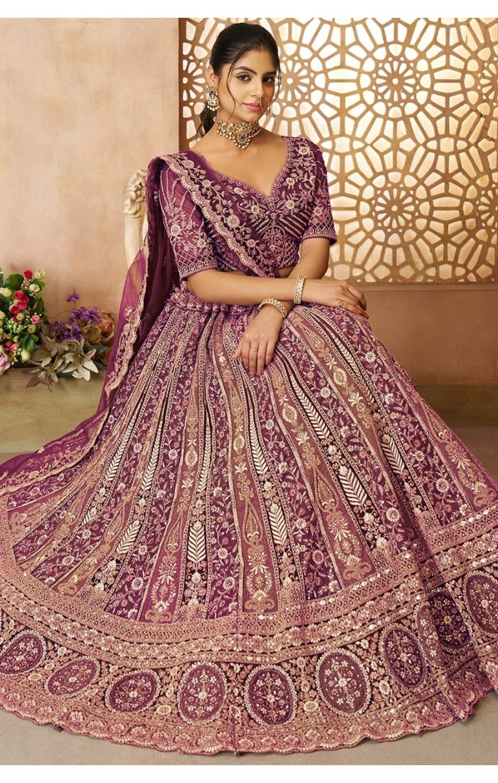  Model seated in paneled soft net purple lehenga for bridal wear