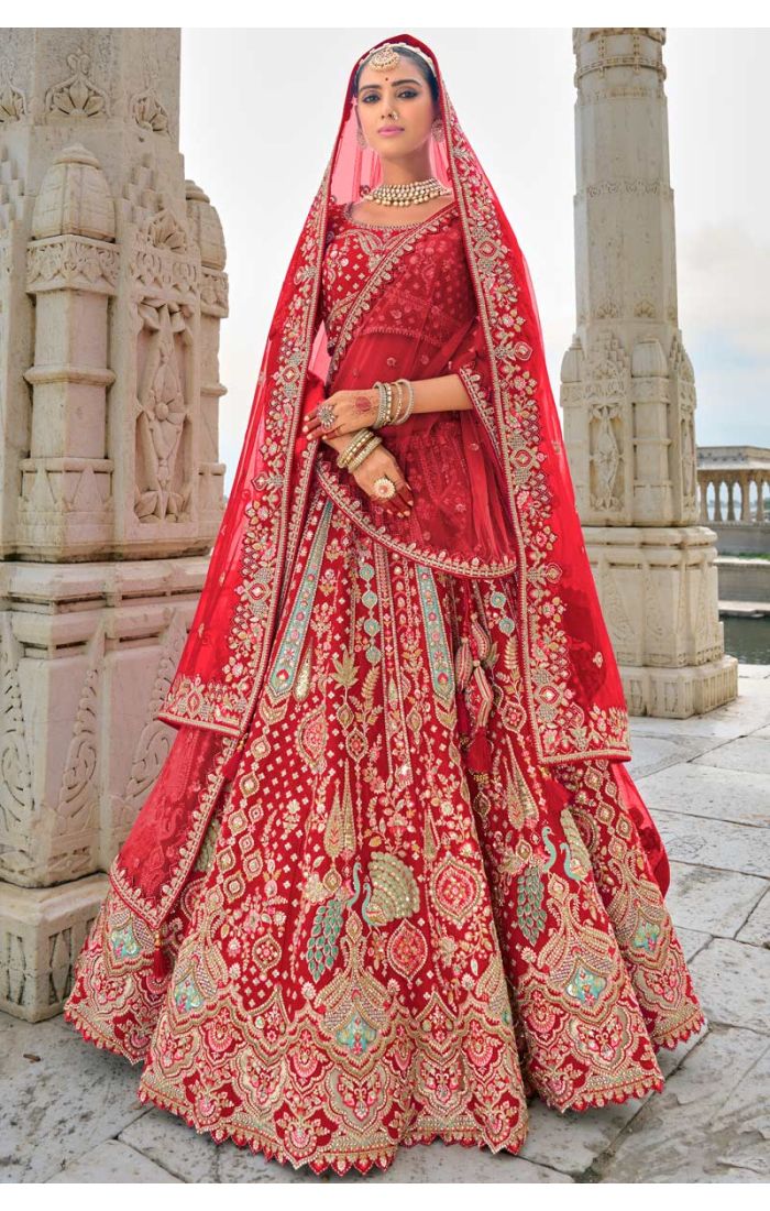 Red bridal lehenga with Zardosi embroidery and peacock motifs paired with a sheer dupatta for traditional weddings.