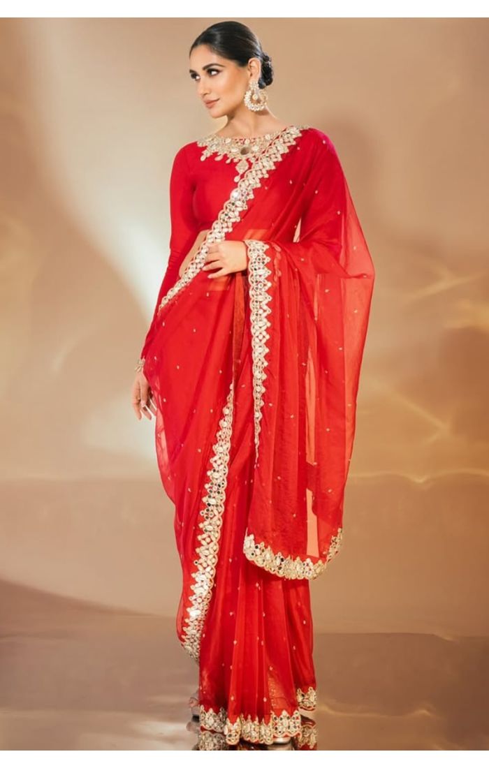  Side pose of model in red saree highlighting border embroidery and graceful drape.