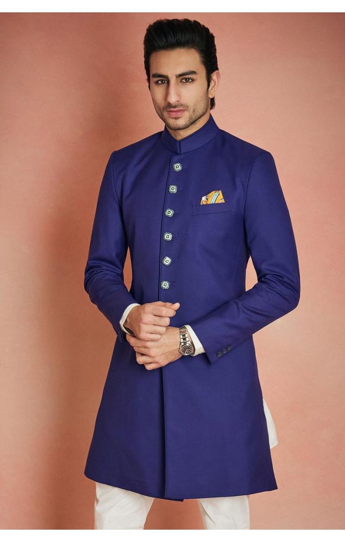 Men’s royal blue Indo-Western sherwani with silver-tone buttons, mandarin collar, and white pants, perfect for weddings and festive occasions.