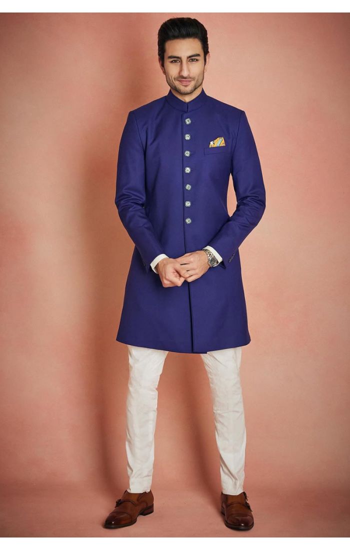 Men’s royal blue Indo-Western sherwani with silver-tone buttons, mandarin collar, and white pants, perfect for weddings and festive occasions.