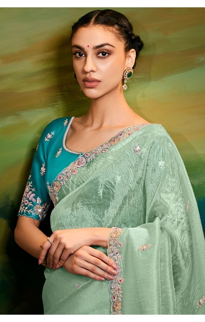 Close-up of embroidery details on sea green saree and lace border