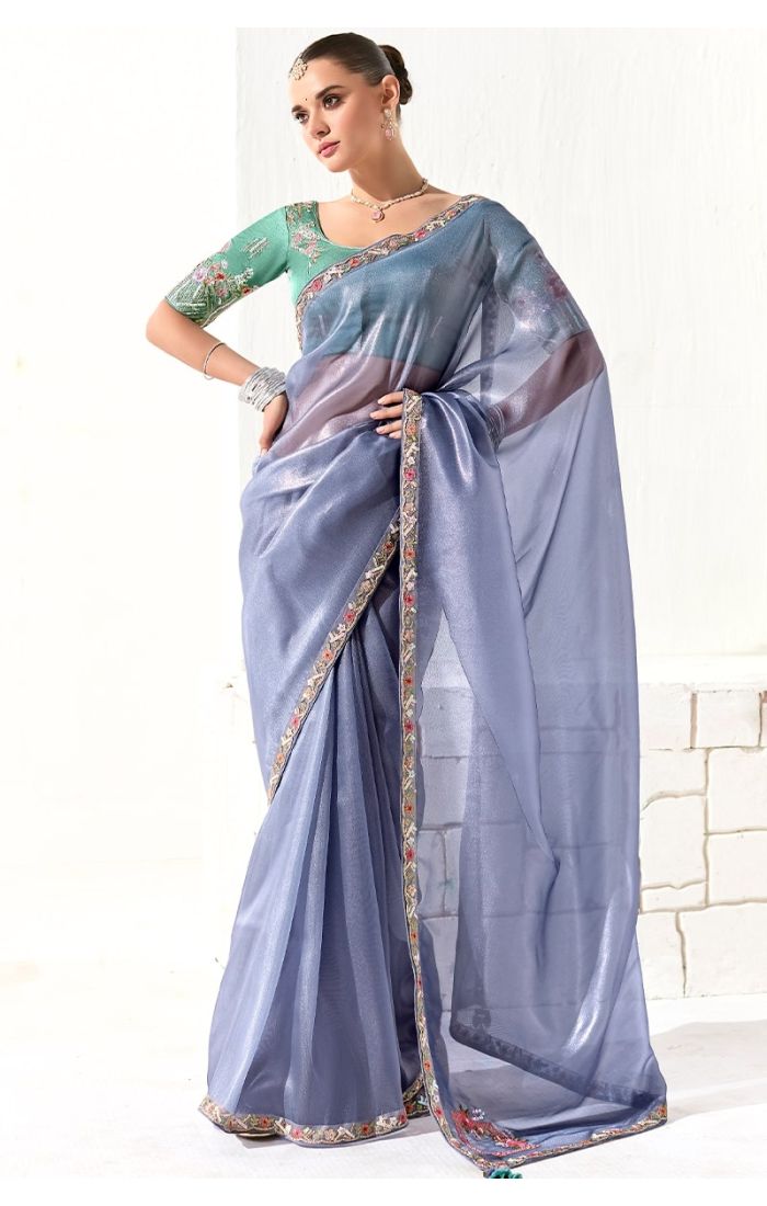 Model wearing sky blue organza tissue silk saree with embroidered blouse and lace border
