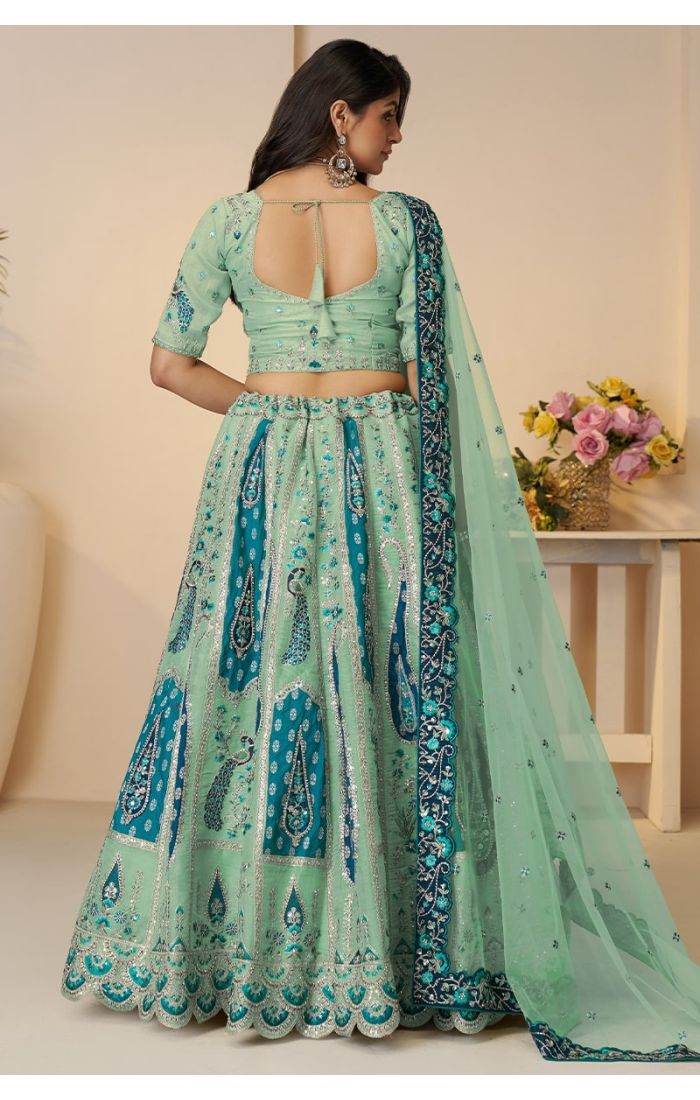 Back view showing keyhole blouse design and full lehenga flare in blue embroidery.