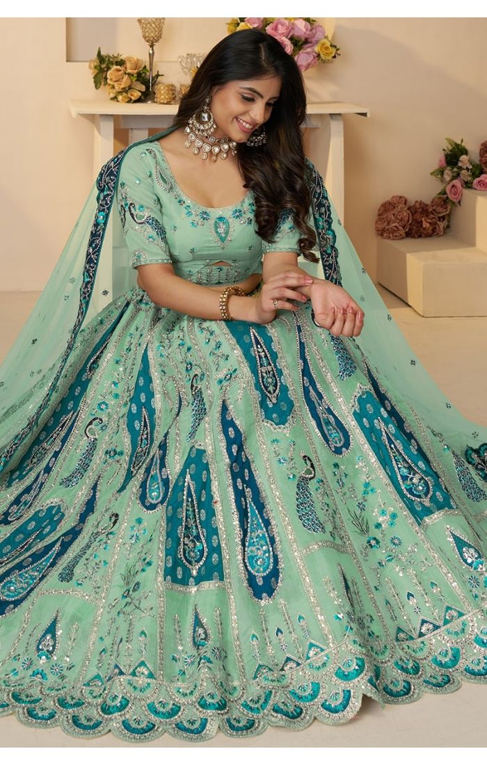 Model sitting in peacock embroidered lehenga, showcasing net dupatta and heavy flare.