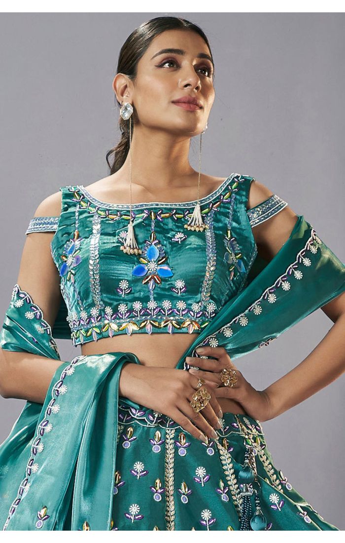 Close-up of teal green designer lehenga choli blouse with multicolour embroidery and mirror work detailing