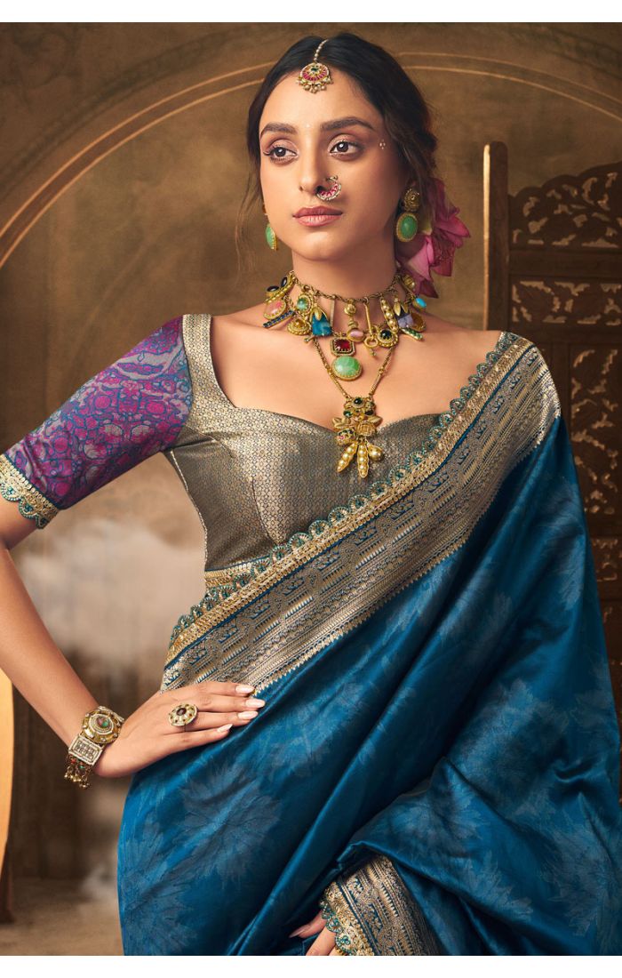 Close-up of gold zari border and designer blouse on teal silk saree