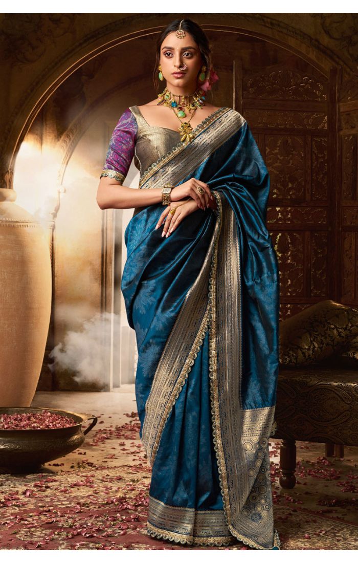 Woman wearing teal silk saree with gold zari border – front view