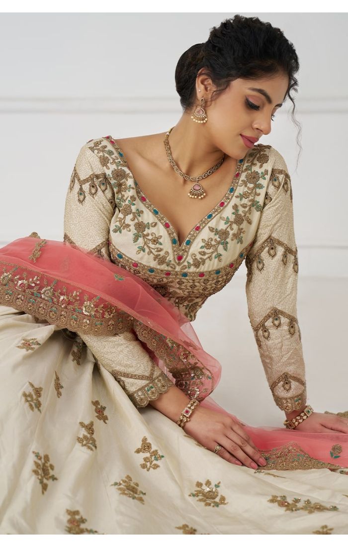 Ivory lehenga with peach net dupatta styled in traditional Indian setting